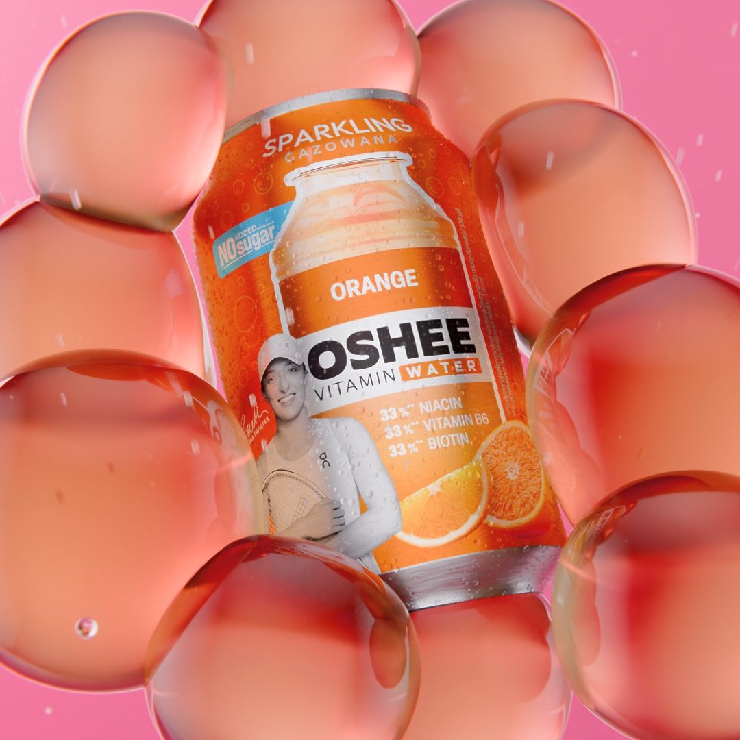 OSHEE Sparkling Vitamin Water orange can with no added sugar, tennis player Iga Świątek printed on the label, nested inside a cluster of translucent coral bubbles on pink, 3D CGI product render