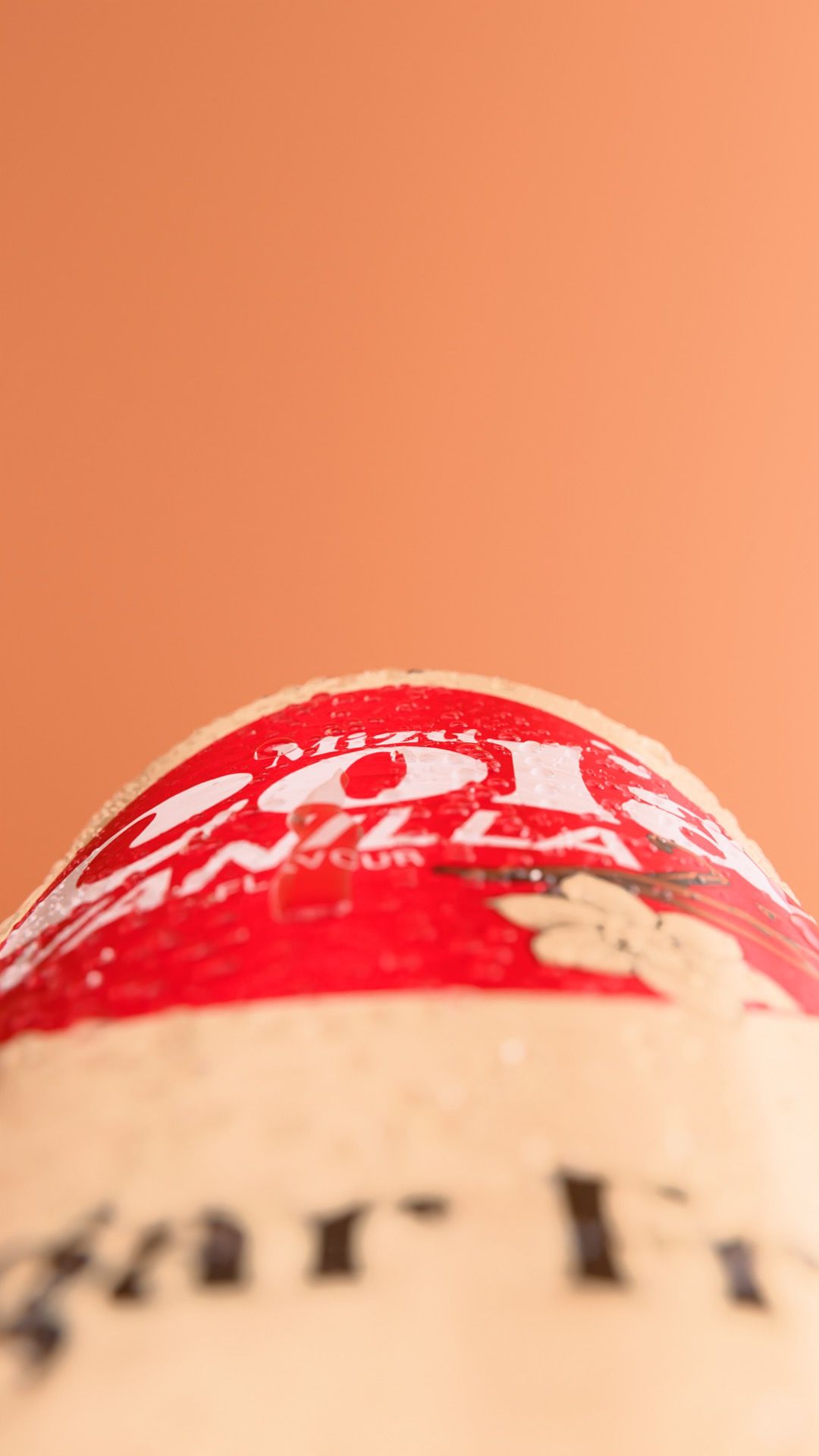 Extreme macro of the Vitamizu Mizu Cola Vanilla can, its red label disc and 'Sugar Free' line beaded with condensation against a peach background, vertical 3D CGI product render