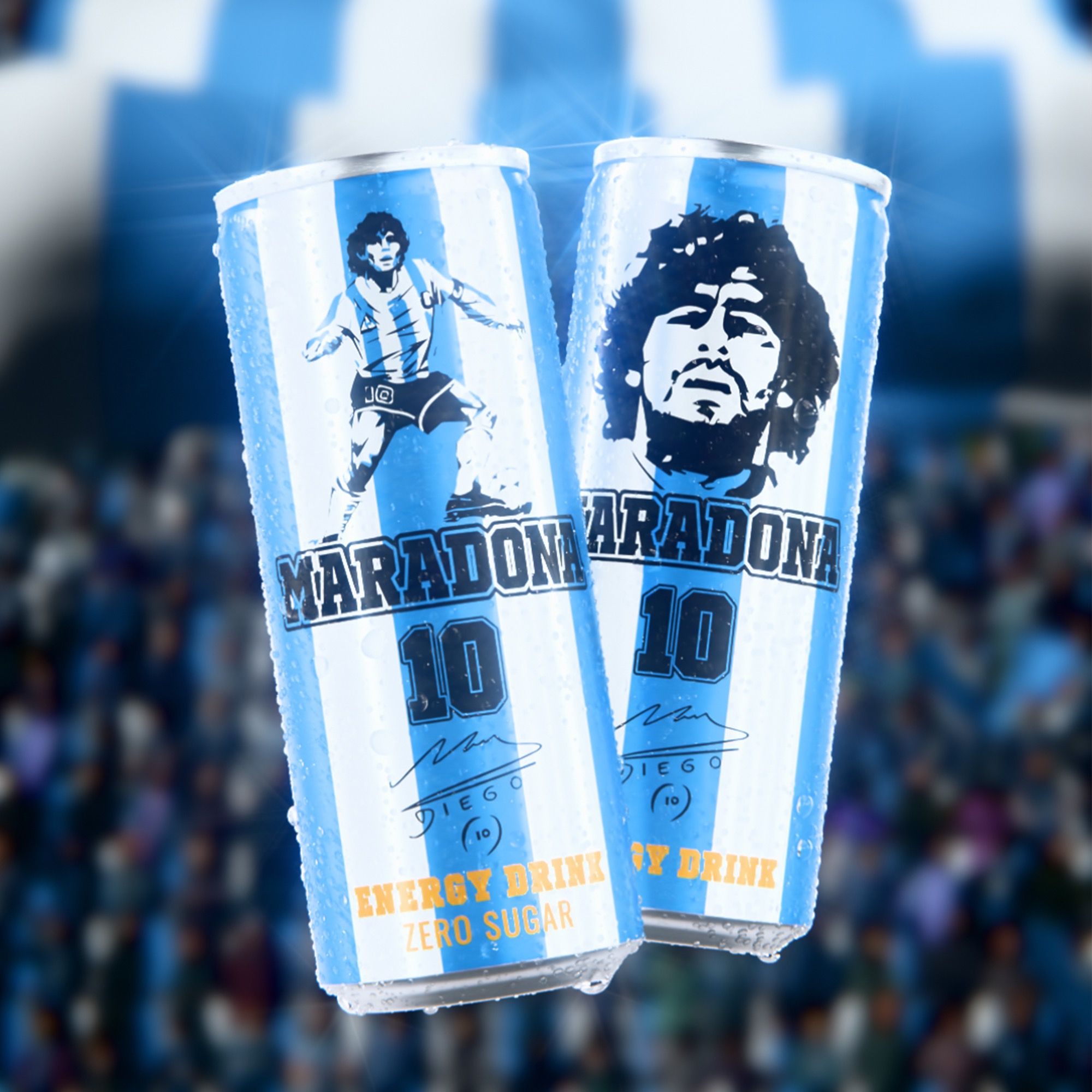 Two Vitamizu Maradona zero-sugar energy drink cans in Argentina light-blue-and-white stripes, one with a stencilled Diego Maradona portrait, one with the number 10, floating in front of a blurred stadium crowd, 3D CGI product render